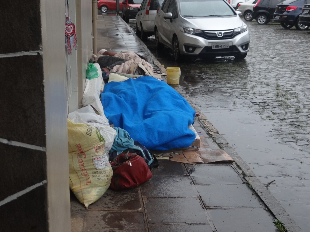 Na chuva, pessoas estão dormindo atrás da rodoviária de Garibaldi